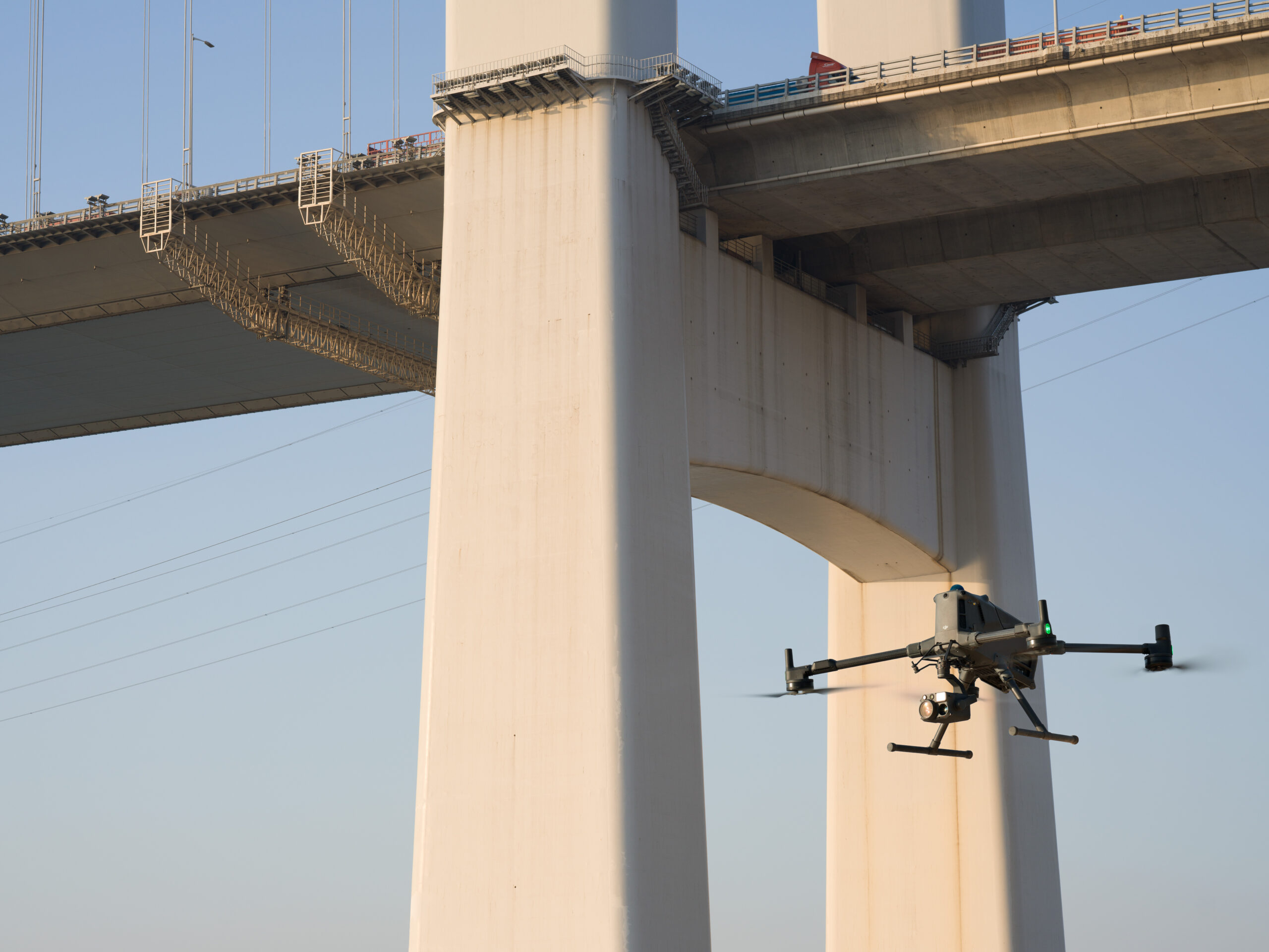 Drohne mit Zenmuse H30T Kamera fliegt an den Betonpfeilern einer großen Brücke entlang