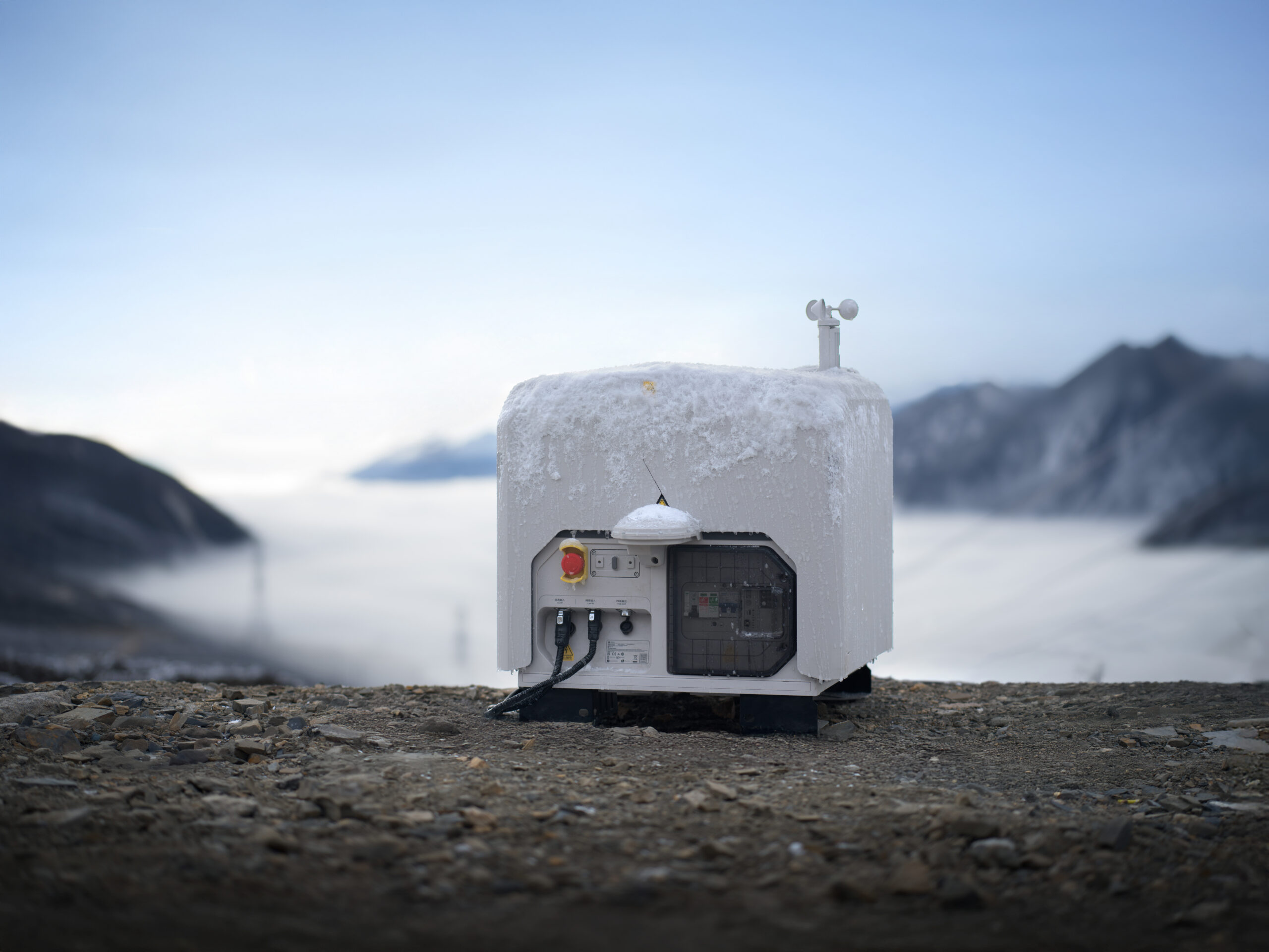 Schneebedeckte DJI Dock 3 Drohnenstation im Gebirge über einem Nebelmeer