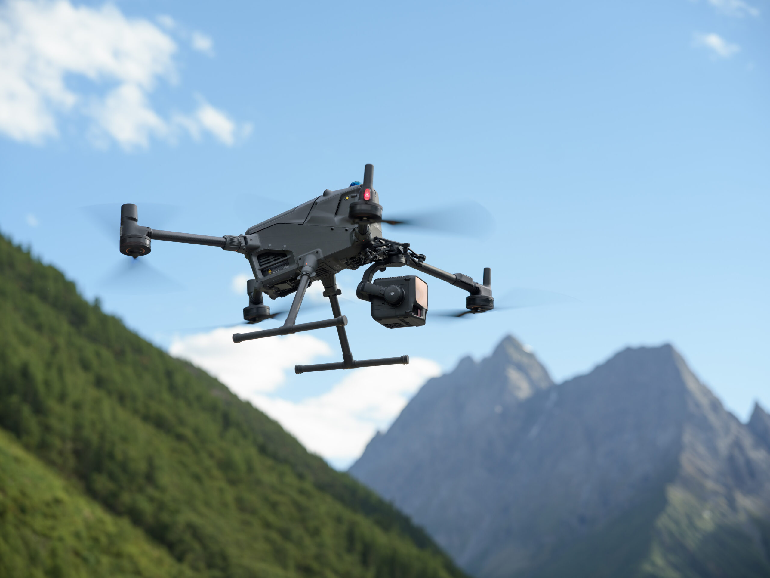 Vermessungsdrohne mit Zenmuse L3 LiDAR-Sensor fliegt vor Bergwald und Felsgipfel
