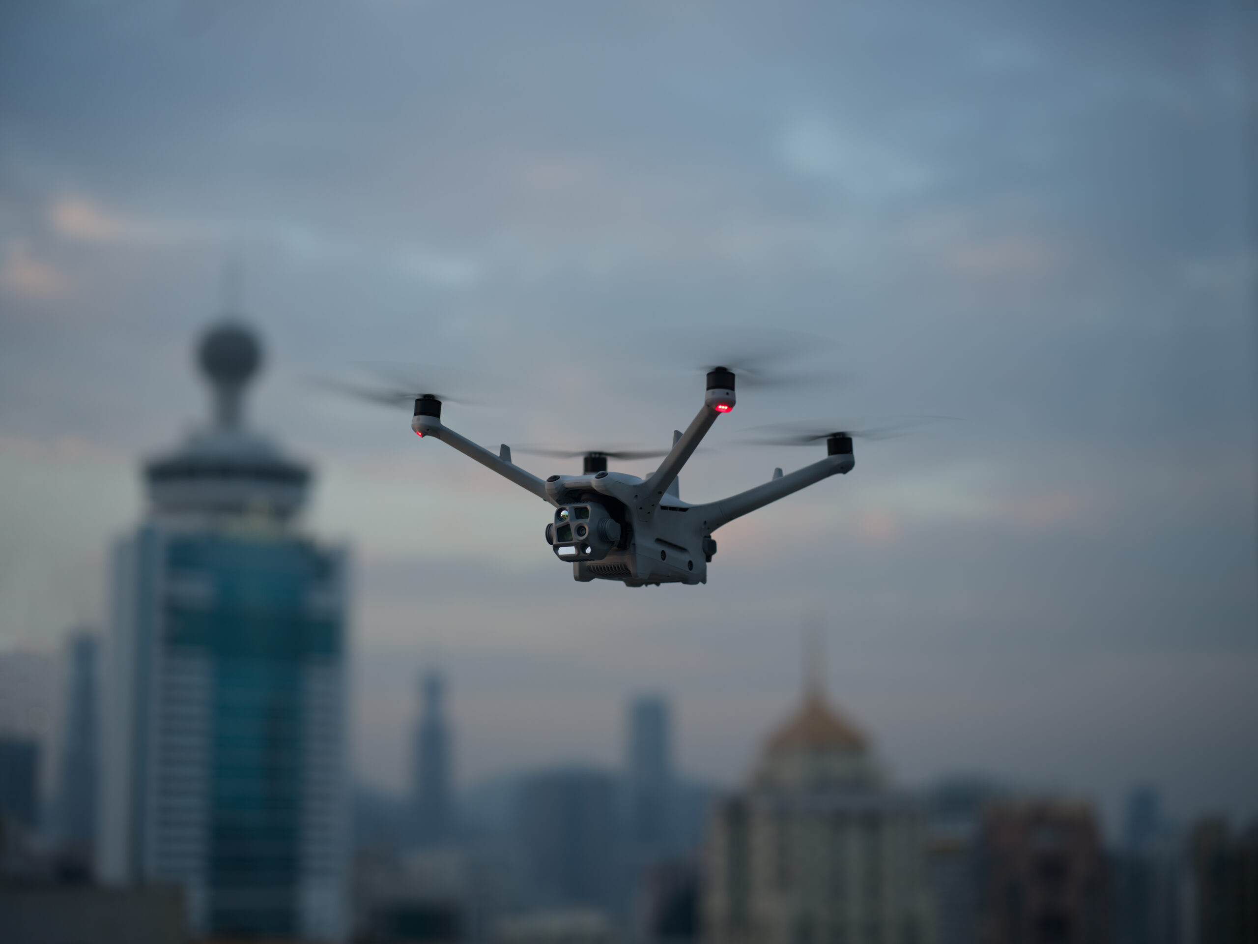 DJI Matrice 4TD fliegt in der Abenddämmerung über einer Stadt mit Hochhäusern