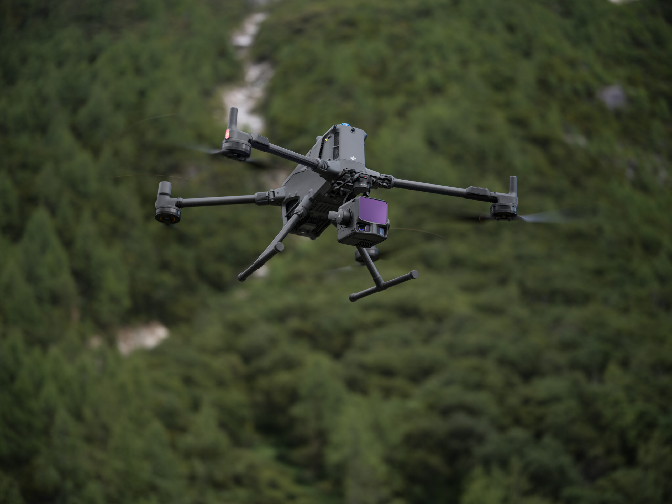 Drohne mit Zenmuse L3 LiDAR-Sensor im Flug über einem dicht bewaldeten Berghang