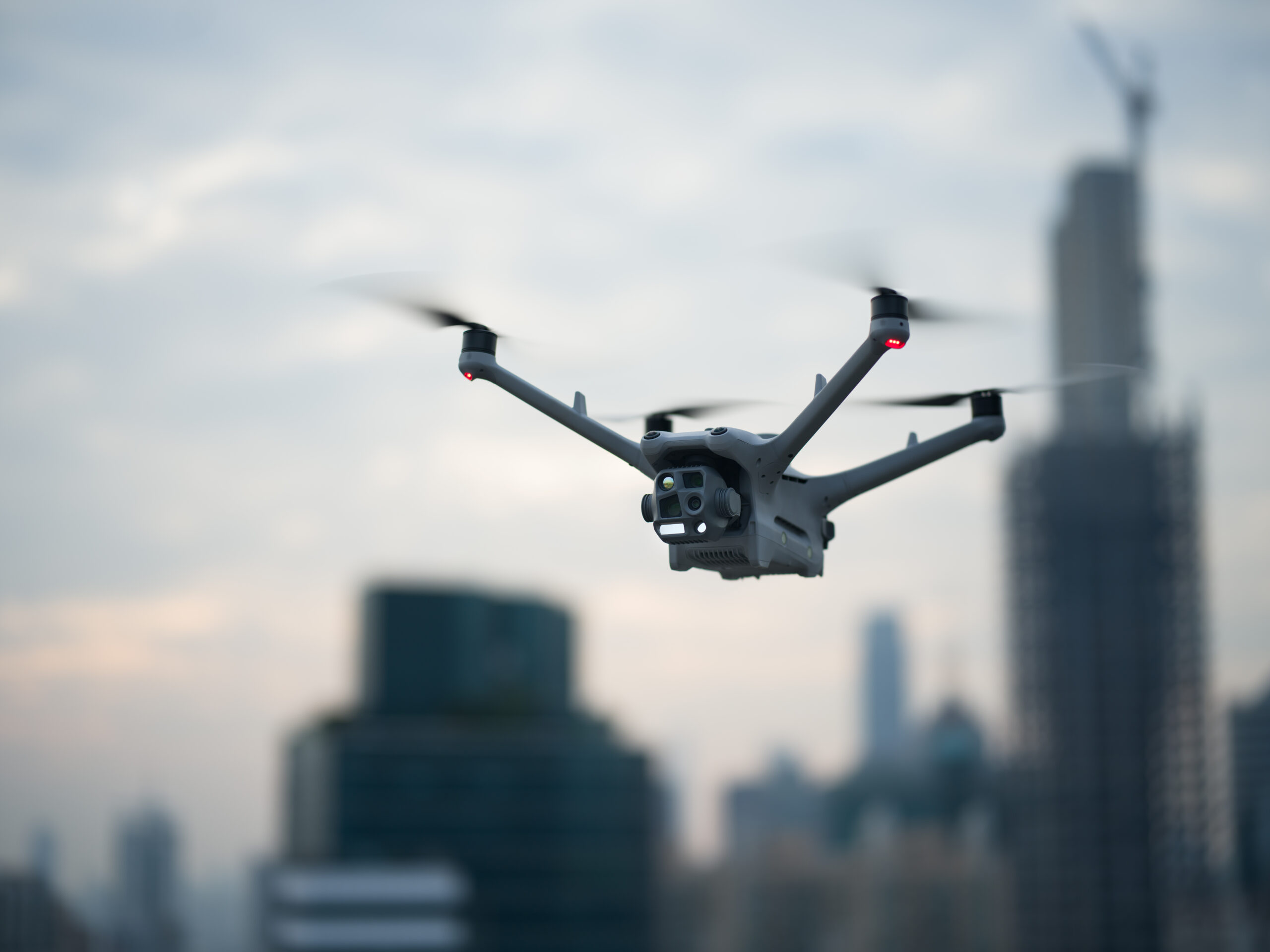 Drohne mit Mehrfachkamera fliegt über einer Stadt mit Hochhäusern und Baukran